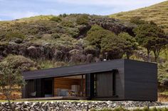 a small black house sitting on top of a lush green hillside