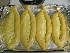 four pieces of bread sitting on top of tin foil covered in yellow sauce and cheese