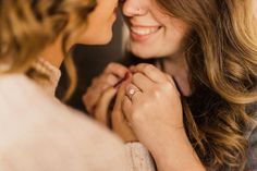 two women who are touching each other's hands and looking at each other with smiles on their faces