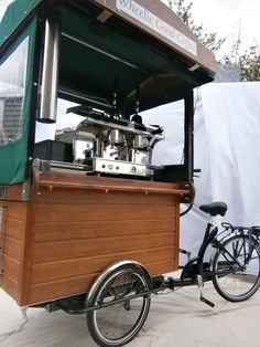 a bike parked next to a food cart with a coffee machine on the top and side