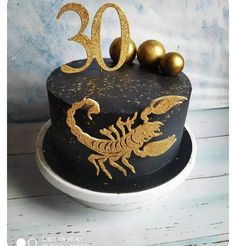 a black cake with gold decorations and a scorpion on the top that reads 30 years