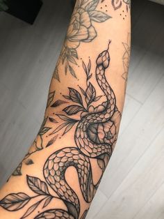 a person with a tattoo on their arm that has a snake and flowers on it