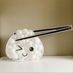 a white sushi with chopsticks sticking out of it's head and eyes