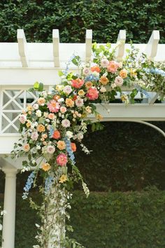 an outdoor wedding ceremony setup with flowers and greenery on the side of the aisle