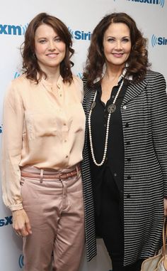 two women standing next to each other in front of a wall with the sirius logo on it