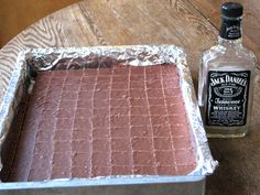 a cake sitting on top of a pan covered in tin foil next to a bottle of whiskey