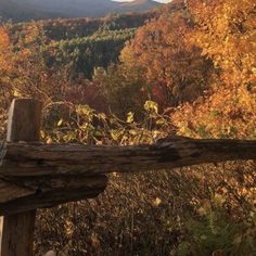 a wooden fence in front of some trees with fall foliage on the mountains behind it