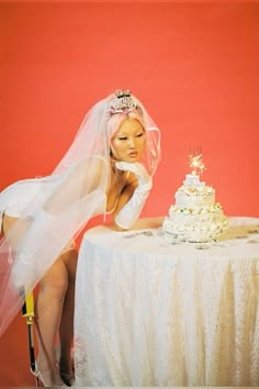 a woman sitting at a table in front of a cake with a veil over her head