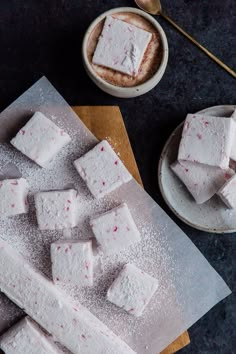 marshmallows on a cutting board next to a cup of coffee