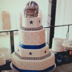 a three tiered cake with a football helmet on the top and stars on the bottom