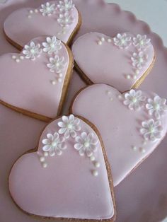 some heart shaped cookies are on a plate with flowers and pearls in the middle,