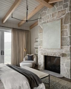 a bedroom with a stone fireplace and white bedding