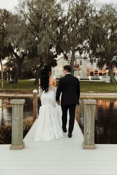 a bride and groom walking on a dock