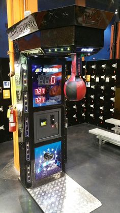 an arcade machine with boxing gloves hanging from it's sides in a room full of lockers