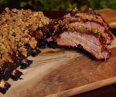 two pieces of meat sitting on top of a wooden cutting board next to each other