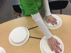 a person with their hands on top of some paper plates at a table in an office