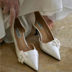 a close up of a person wearing white shoes with flowers on the toes and heels