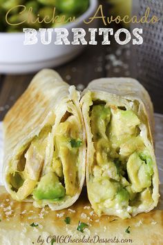 a burrito cut in half on top of a cutting board with cheese and avocado