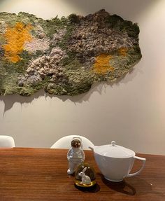 an astronaut statue sitting on top of a wooden table next to a vase and bowl