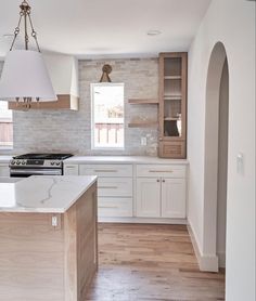 an empty kitchen with white cabinets and wood flooring on the countertops, along with a large island