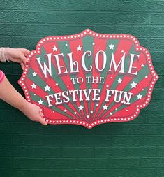 a person holding a sign that says welcome to the festive fun