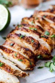 sliced chicken breast with parsley and lime on cutting board next to lemon wedges