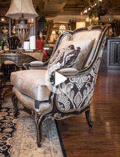 an ornate chair and ottoman in a large room with wood floors, chandeliers and lamps