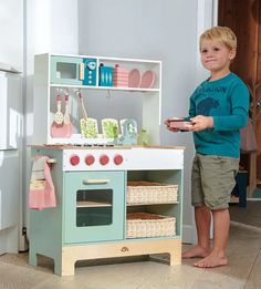 a young boy standing in front of a toy kitchen