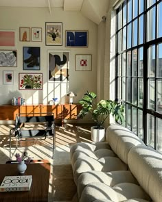 a living room filled with lots of windows next to a wall covered in framed pictures