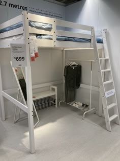 the bunk bed is white and has two ladders on each side, which are also used as a desk