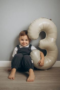 a young boy sitting on the floor with an inflatable number