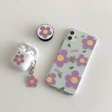 an iphone case with flowers on it next to ear buds and a keychain