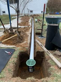 a pipe laying in the ground next to some construction materials and tools on the ground