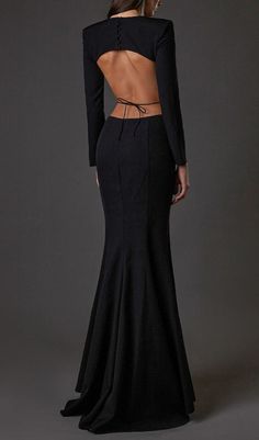 the back of a woman in a black dress with cutouts on her chest and long sleeves