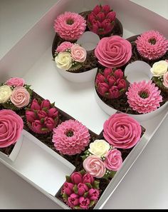 a box filled with cupcakes covered in pink and white frosting flowers on top of each other