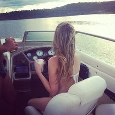 a man and woman sitting in the back of a boat on a body of water