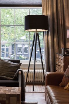 a living room with a couch, chair and lamp in front of a large window