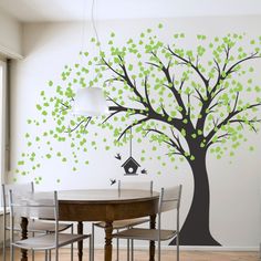 a tree with green leaves painted on the wall next to a dining room table and chairs