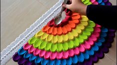 a person cutting paper with scissors on top of a colorful table cloth that is shaped like a fan