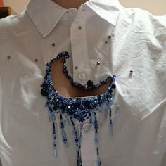 a white shirt with blue beads on it