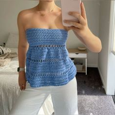 a woman taking a selfie with her cell phone in front of her face and wearing a blue crocheted top