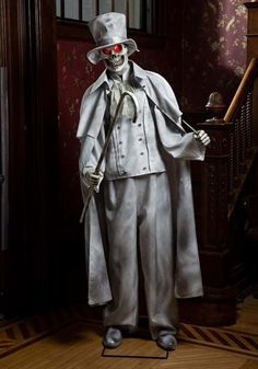 a skeleton dressed in white with a top hat and cane standing next to a stair case