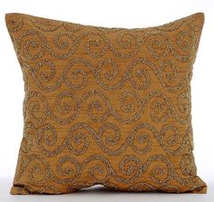 a gold pillow with an intricate design on the front and back, sitting against a white background