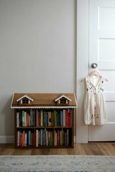 a book shelf with books and a doll house on top