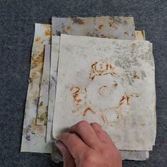 a person's hand is pointing at some old papers on the floor with rusted edges