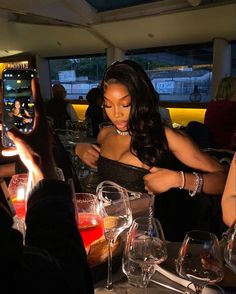 a woman in a black dress taking a photo with her cell phone at a restaurant