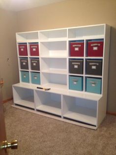 a white bookcase with blue and red bins on it's sides in a room