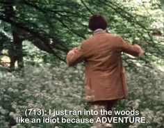 a man in a brown coat is walking through the woods with his back to the camera