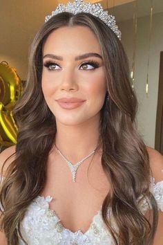 a woman wearing a tiara and smiling at the camera with balloons in the background