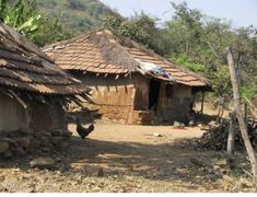 two chickens are standing in front of small huts with thatched roofs and straw bales